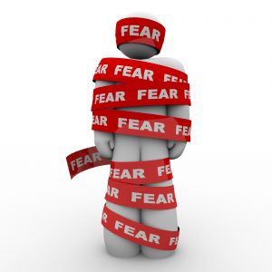 Morph-like cartoon humanoid wrapped up in red tape that says FEAR on it